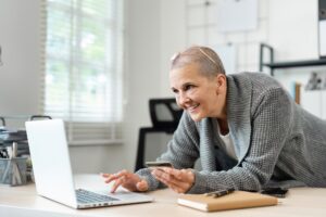 Senior Woman Shopping Online with Credit Card and Laptop in Modern Home Office Setting